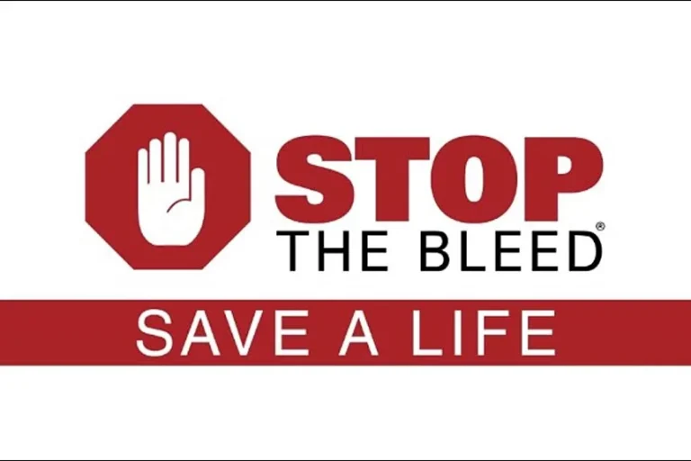 A red stop sign with a white hand next to the words "STOP THE BLEED" above a red bar that says "SAVE A LIFE" in white letters.
